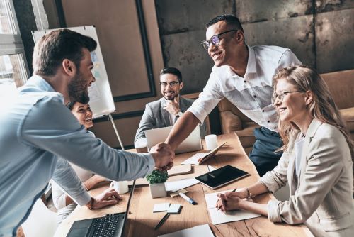 Business man shaking hands with patent attorney over table in meeting.