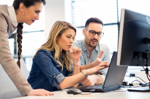 Businessman and two businesswomen looking at a computer screen.